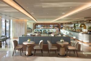 a restaurant with tables and chairs and a bar at The Meydan Hotel Dubai in Dubai +42 photos