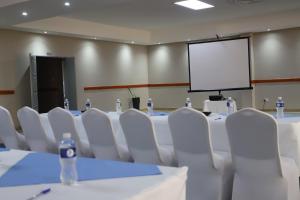 a conference room with white tables and chairs and a screen at Dikukama Executive Hotel in Tshabong