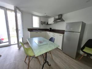 a kitchen with a table and chairs and a refrigerator at Chez Helje in Les Essards-Taignevaux