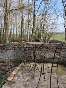 a table and two chairs next to a stone wall at Chez Helje in Les Essards-Taignevaux