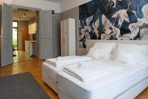 a white bed in a room with a painting on the wall at Csaba Vendégház in Izsák