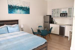 1 dormitorio con cama, mesa y cocina en Smugglers Inn Studio Apartments, en Victor Harbor