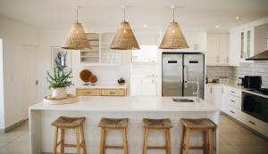a kitchen with a white island with bar stools at White Wicker House in Langebaan +16 photos