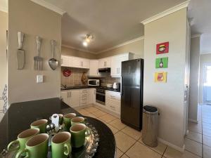 a kitchen with a black refrigerator and green mugs on a counter at Boardwalk 11 in Struisbaai +3 photos
