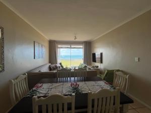 a dining room with a table and chairs and a window at Boardwalk 11 in Struisbaai