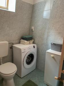 a bathroom with a washing machine and a toilet at Hársfa Central Apartment in Mórahalom +2 photos