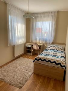 a bedroom with a bed and a desk and window at Hársfa Central Apartment in Mórahalom