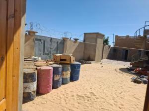 a group of barrels sitting in the sand next to a building at ramadan in Tombouctou
