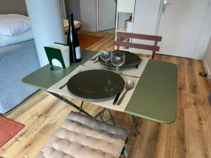 a green table with two glasses and a bottle of wine at Chambre-Studio et SAUNA indépendants in Annecy +2 photos