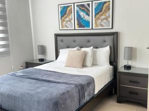 a bedroom with a bed with three paintings on the wall at Parkhurst Lux Condo Near Devon House in Kingston