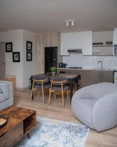 a kitchen and living room with a table and chairs at Beachside Modern Holiday Apartments in Cape Town