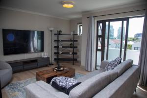 a living room with a couch and a flat screen tv at Beachside Modern Holiday Apartments in Cape Town