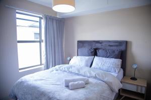 a bedroom with a large bed with two towels on it at Beachside Modern Holiday Apartments in Cape Town
