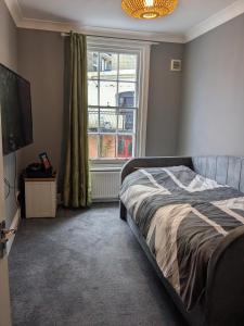 a bedroom with a bed and a large window at Seaside 4 bed terraced house in Hastings