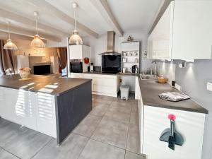 a kitchen with white cabinets and a black counter top at Maison 4 ch, véranda, proche commodités, Aurillac in Aurillac
