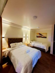 a hotel room with two beds with white sheets at MAR y LAGO EXPERIENCE in Lunahuaná