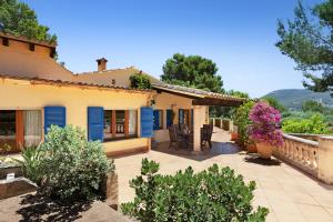 a house with blue shutters and a patio at Villa Sophia in Port d'Andratx