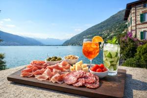 a tray of meat and cheese and drinks on a table next to a lake at Villa Marina - Como lake in Bellano