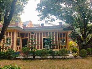 a yellow house with trees in front of it at Corbett Bungalow Stay- Private Garden Stay Near Jim Corbett in Rāmnagar +23 photos