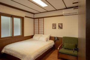 a small bedroom with a bed and a green chair at Staykor Busan in Pusan