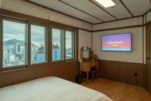 a bedroom with a bed and a tv on the wall at Staykor Busan in Pusan