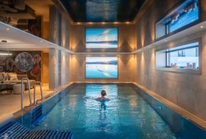 a woman in a swimming pool with two windows at Hotel Bergkristall Oberlech in Lech am Arlberg