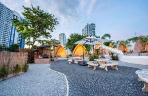 a park with benches and tables and umbrellas at kingdom glamping in North Pattaya