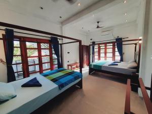 two beds in a room with two windows at Drift Bay in Arugam Bay