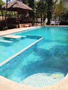a large swimming pool with blue water at MALKIA SUITEs in Diani Beach