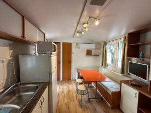 a small kitchen with a table in a tiny house at Camping Bi Village - Maeva Vacansoleil in Valbandon