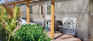 a patio with a table and chairs and a sign at Ánizs Apartmanház in Makó