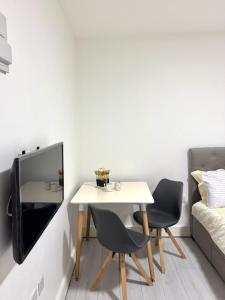 a table and two chairs and a tv in a room at Cozy Golders Green Studio Flat in Moffat