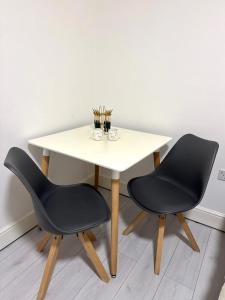 a table with two chairs and a white table with a table at Cozy Golders Green Studio Flat in Moffat