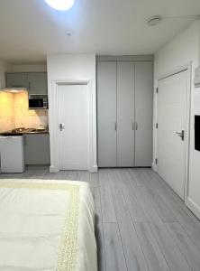 a white bedroom with white cabinets and a kitchen at Cozy Golders Green Studio Flat in Moffat