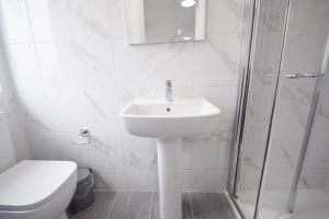a white bathroom with a sink and a toilet at Cozy Golders Green Studio Flat in Moffat