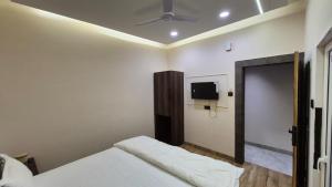 a bedroom with two beds and a tv on the wall at Hotel MRK VILLA in Varanasi