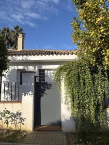 a white house with a door and a hedge at Studio-Guest House with Jacuzzi Spa and Sauna in Espartinas