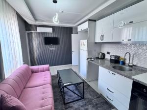 a living room with a pink couch and a kitchen at Ege Suit in Buca