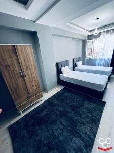 a bedroom with two beds and a wooden cabinet at Ege Suit in Buca