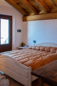 a large bed in a room with a wooden ceiling at Chalet Burrino in Frabosa Soprana