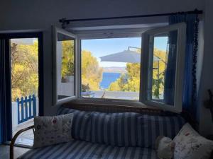 a living room with a couch and two windows at Charming Spetses Studio with Outdoor Space in Spetses
