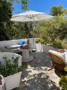a patio with a table and an umbrella and chairs at Charming Spetses Studio with Outdoor Space in Spetses