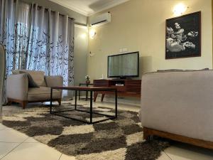 a living room with a tv and two chairs and a table at TheGatsbyStyle by EcoPact in Dar es Salaam