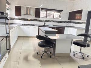 a kitchen with white cabinets and black chairs in it at Palm Guesthouse in Zeerust