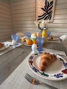 a table with a plate with a croissant on it at Casa Rosa - Sfeervolle cottage met jacuzzi in Erm