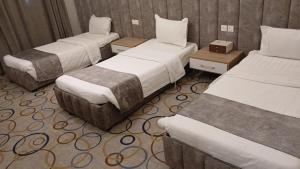 a hotel room with three beds in a room at شقق أبهى المضياف الذهبية للشقق المخدومة in Abha
