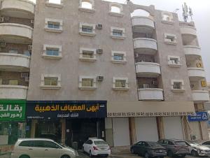 a large building with cars parked in front of it at شقق أبهى المضياف الذهبية للشقق المخدومة in Abha