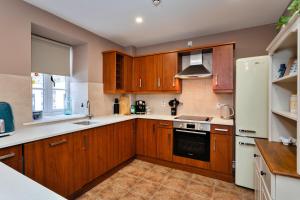 a kitchen with wooden cabinets and a white refrigerator at Finest Retreats - The Kiln in Bamburgh
