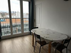 a table and chairs in a room with a large window at Paris visite in Ivry-sur-Seine