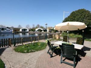 a table and chairs with an umbrella next to a river at Aquaronde 129 in Lemmer